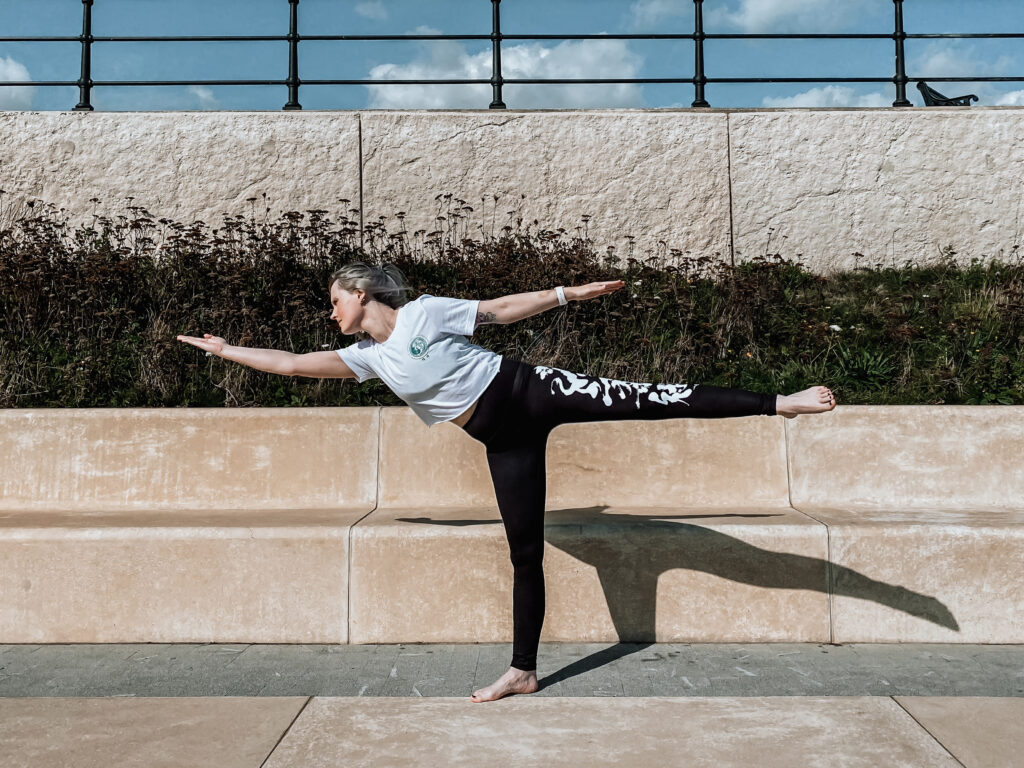 A girl outside in flying warrior yoga pose